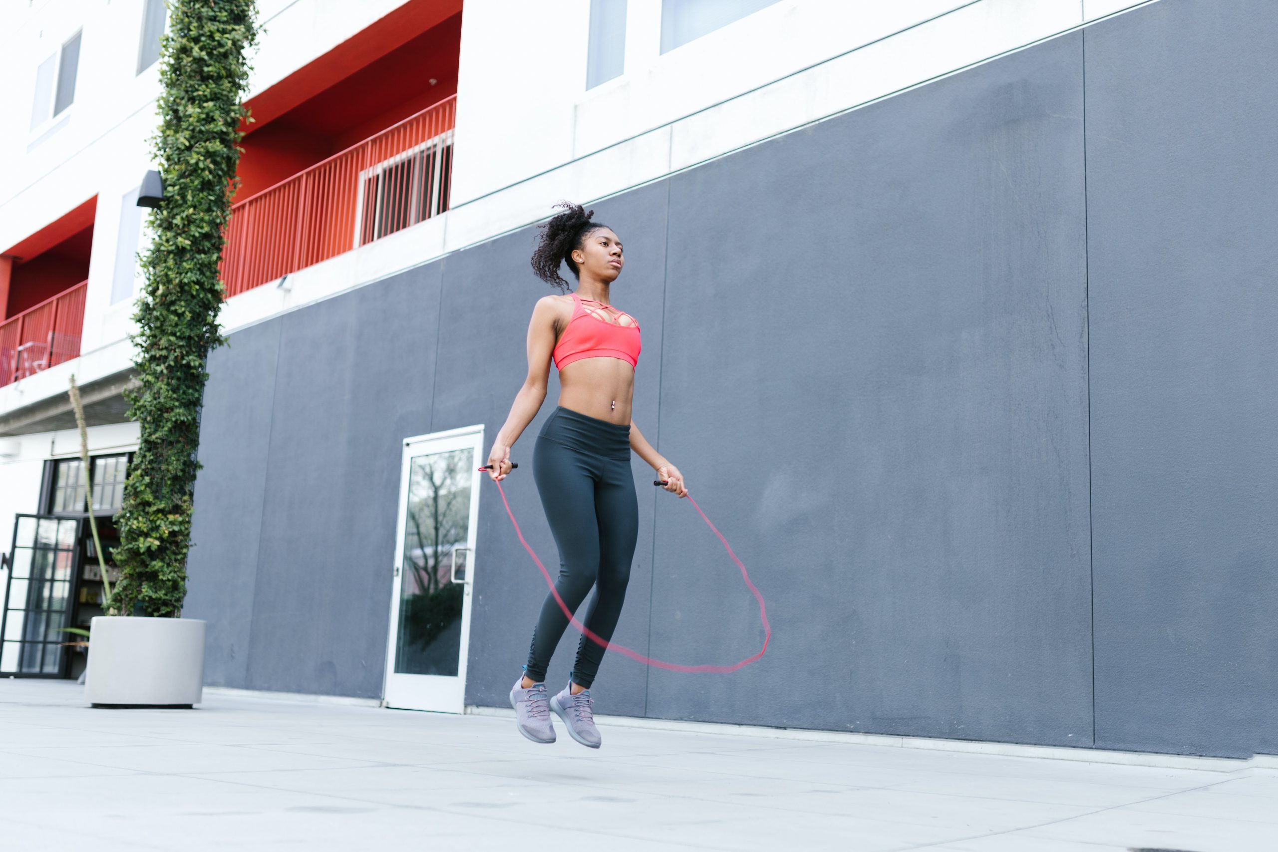 Une femme en tenue de sport fait de la corde à sauter dans la rue. Elle prépare son summer body.